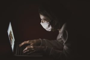 Mujer con máscara quirúrgica navegando en línea
